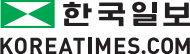 The logo for '한국일보 KOREATIMES.COM,' the oldest and largest circulation Korean-language daily newspaper in the USA, originally established in 1969 as the the US distribution arm of 'Hangook Ilbo,' is a green rectangle containing two opposing green triangles on the x-axis and two opposing white triangles on the y-axis. On the right of this is their name '한국일보' (pronounced 'han-gug-il-bo' and literally translated 'Korea Daily') in Hangeul (Korean alphabet) in a black sans-serif font. Below both of these is their domain name 'KOREATIMES.COM' all caps in a black sans-serif font.